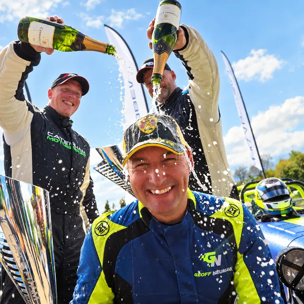 Geoff Newman celebrating a Caterham championship win, with fellow drivers spraying champagne
