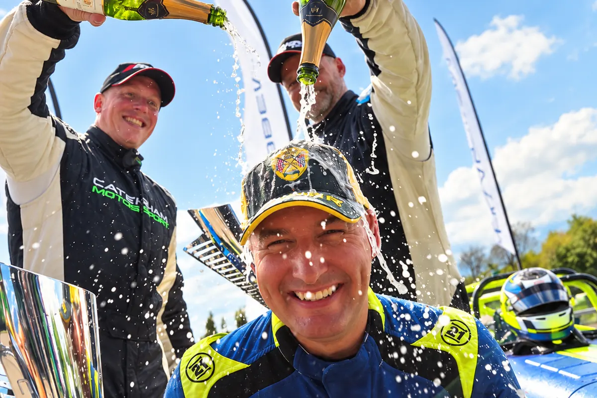 Geoff Newman on the podium, being sprayed with champagne by two fellow Caterham drivers